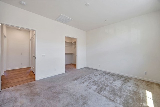 unfurnished bedroom featuring visible vents, a spacious closet, carpet flooring, and baseboards