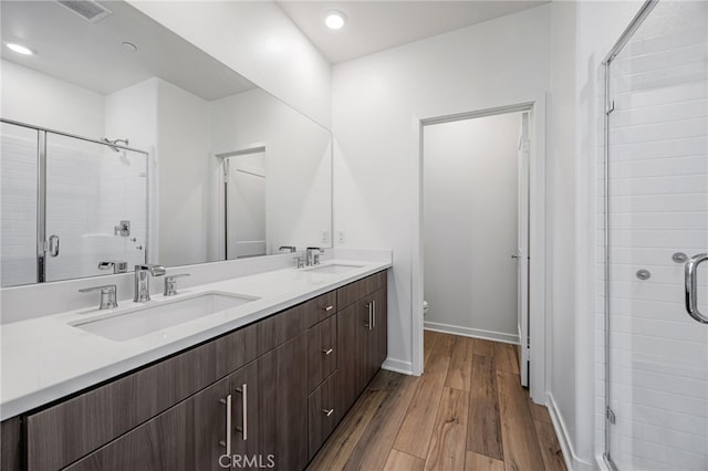 bathroom with visible vents, a stall shower, wood finished floors, and a sink