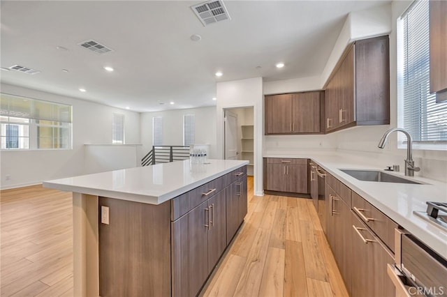 kitchen with a center island, light wood-style floors, light countertops, and a sink