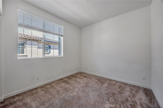 spare room with baseboards and carpet floors