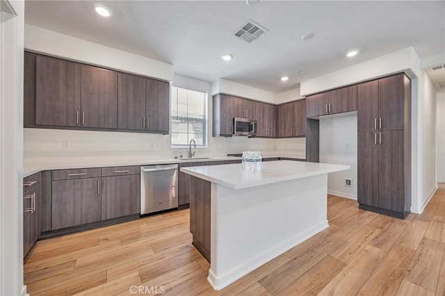 kitchen with a sink, appliances with stainless steel finishes, light wood-style floors, visible vents, and light countertops