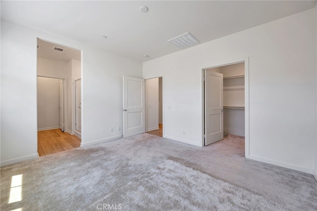 unfurnished bedroom featuring visible vents, carpet flooring, baseboards, and a spacious closet