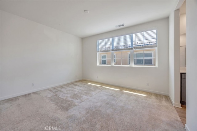 carpeted empty room featuring visible vents and baseboards