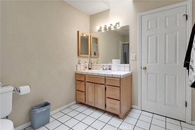 bathroom with toilet, tile patterned floors, vanity, baseboards, and a shower with curtain