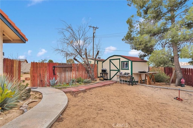 view of yard featuring an outbuilding, a fenced backyard, and a storage unit