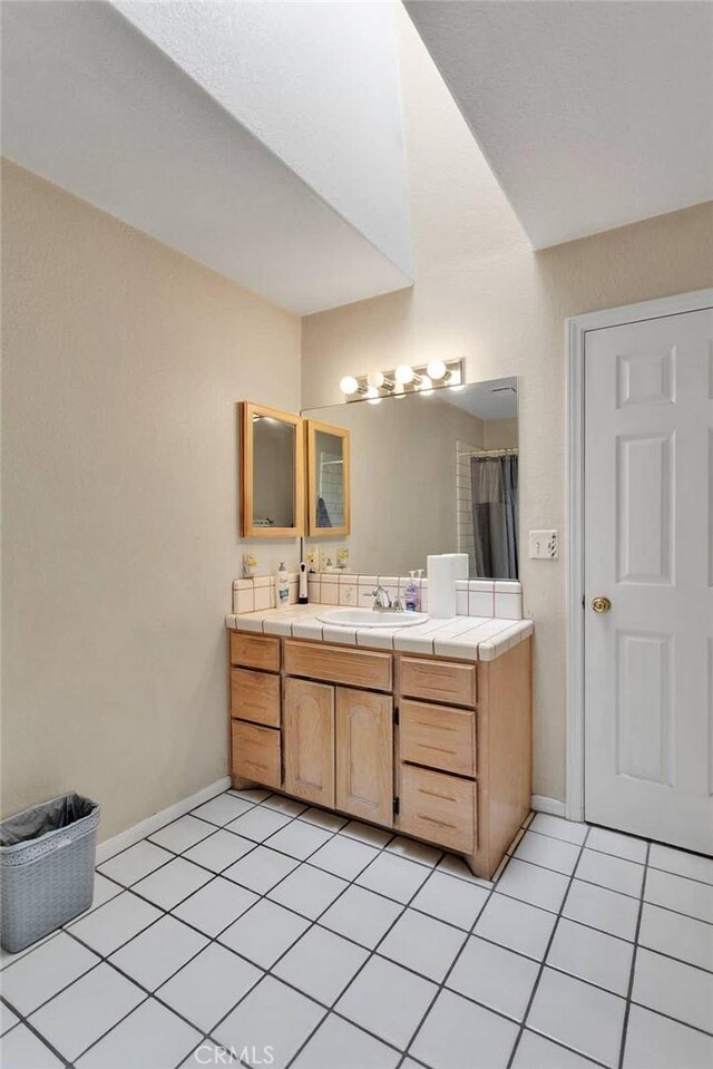 full bathroom with curtained shower, vanity, baseboards, and tile patterned floors