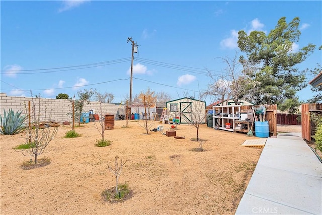 view of yard with a fenced backyard, a storage unit, and an outbuilding