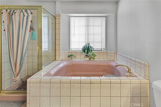 bathroom with a stall shower, a garden tub, and toilet