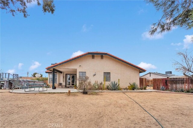 rear view of house with french doors, fence, a patio, and stucco siding