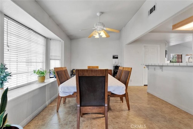 dining room featuring light tile patterned floors, visible vents, vaulted ceiling, ceiling fan, and baseboards