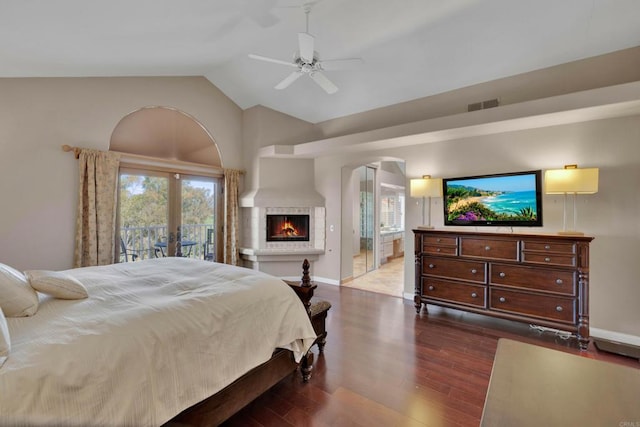 bedroom featuring dark wood-style floors, french doors, visible vents, vaulted ceiling, and a lit fireplace