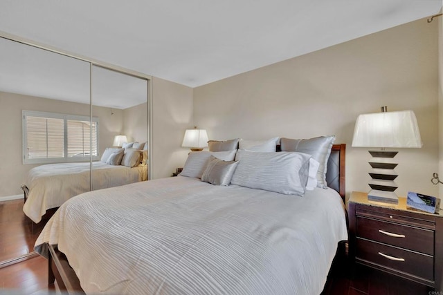 bedroom featuring a closet, dark wood-style flooring, and baseboards