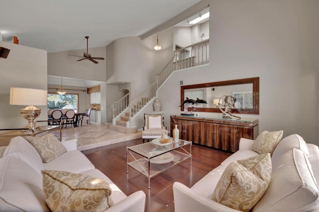 living room with high vaulted ceiling, wood finished floors, ceiling fan, and stairs