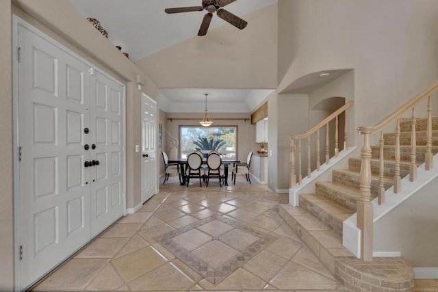 entrance foyer featuring stairway, a ceiling fan, baseboards, and high vaulted ceiling