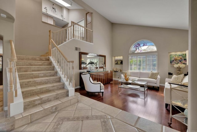 living room with high vaulted ceiling, baseboards, stairway, and wood finished floors