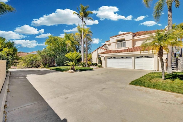 mediterranean / spanish-style house featuring an attached garage, a tiled roof, concrete driveway, and stucco siding