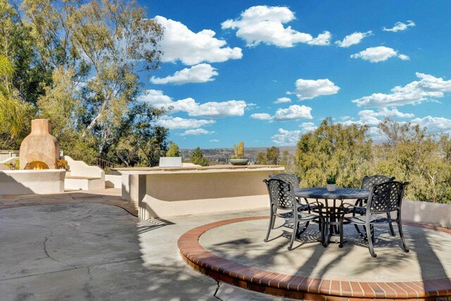 view of patio with a warm lit fireplace and outdoor dining area