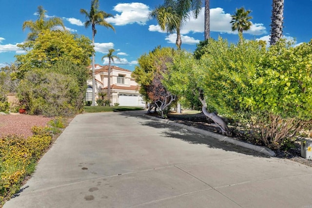 exterior space featuring a garage, concrete driveway, a tiled roof, and stucco siding