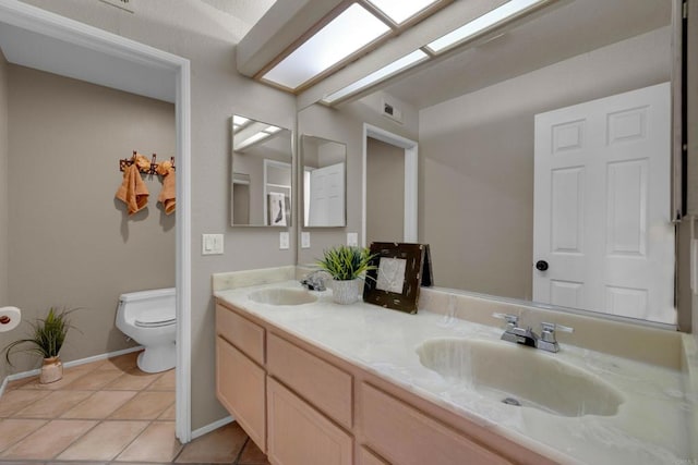 full bathroom with a skylight, a sink, toilet, and double vanity