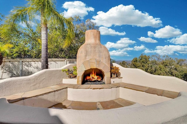 exterior details featuring fence and an outdoor stone fireplace