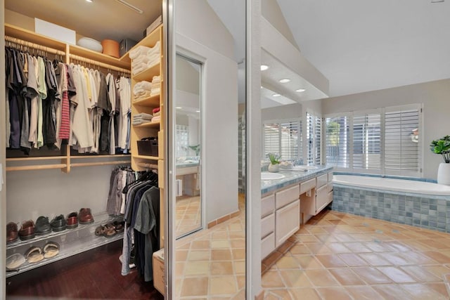 full bath with double vanity, a bath, tile patterned flooring, a spacious closet, and a sink