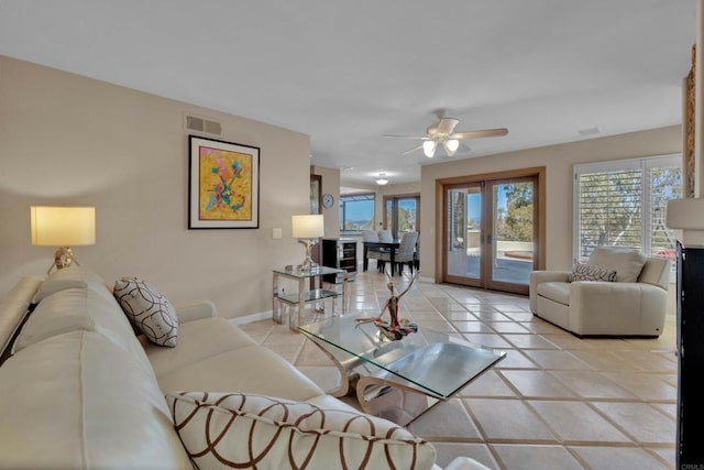 living room featuring french doors, light tile patterned floors, visible vents, a ceiling fan, and baseboards