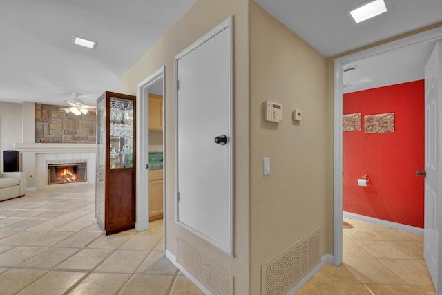 hall with visible vents, baseboards, and light tile patterned floors