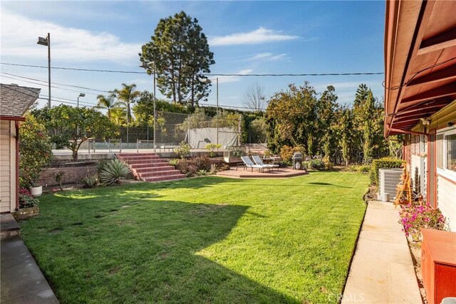 view of yard with a patio area, fence, and central AC