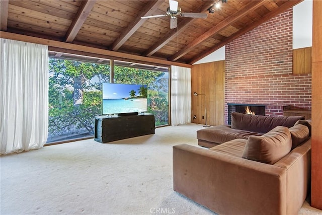 living area featuring wooden ceiling, ceiling fan, carpet flooring, a brick fireplace, and beam ceiling