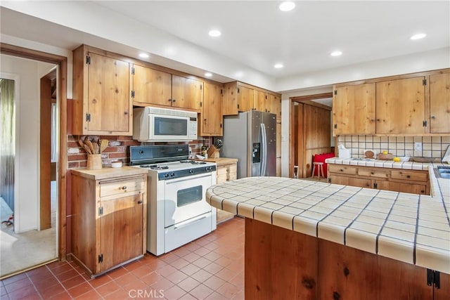 kitchen featuring tile counters, recessed lighting, backsplash, white appliances, and dark tile patterned floors