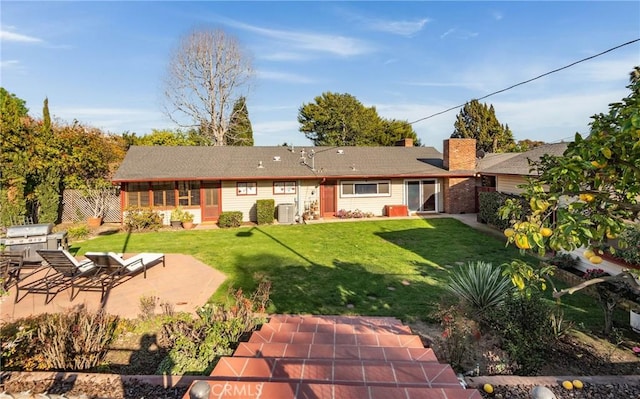 back of property with central AC unit, a patio, a chimney, fence, and a yard