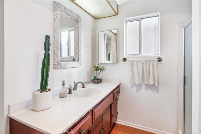 full bathroom featuring an enclosed shower, baseboards, wood finished floors, and vanity