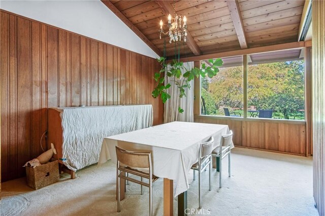 carpeted dining space with lofted ceiling with beams, wood walls, wooden ceiling, and an inviting chandelier