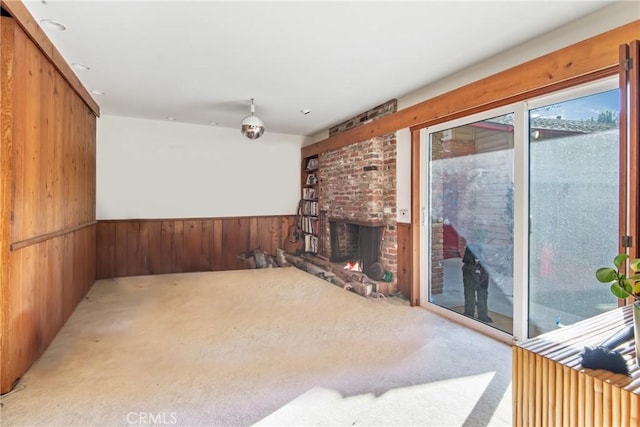 carpeted living area featuring wood walls, a fireplace, and wainscoting