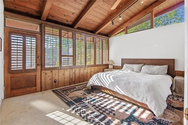 carpeted bedroom featuring vaulted ceiling with beams, wood walls, wood ceiling, and track lighting