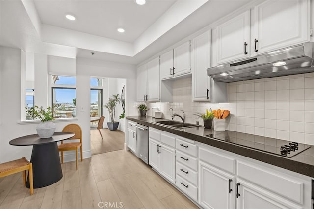 kitchen featuring tasteful backsplash, dark countertops, black electric stovetop, under cabinet range hood, and a sink