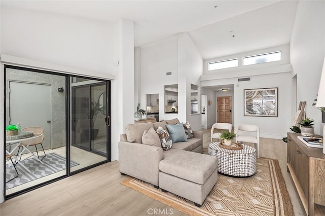 living room featuring visible vents, high vaulted ceiling, and light wood-style flooring