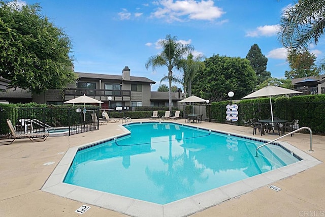 community pool with a patio and fence