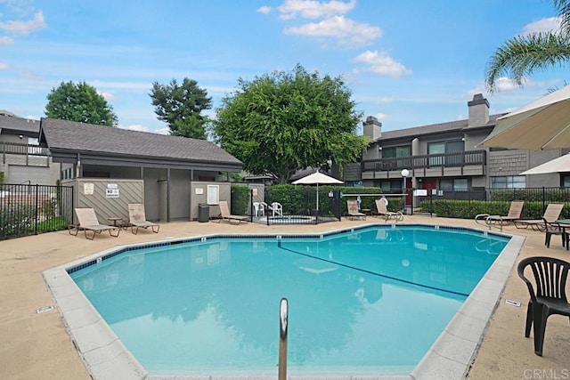 community pool with a patio area and fence