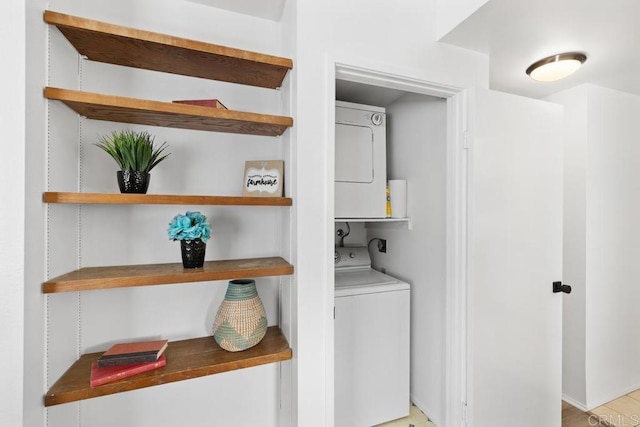 clothes washing area with stacked washer and clothes dryer and laundry area