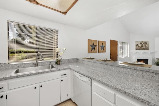 kitchen with a healthy amount of sunlight, white dishwasher, light countertops, and a sink