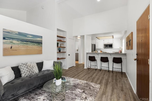 living area featuring built in shelves, high vaulted ceiling, baseboards, and wood finished floors