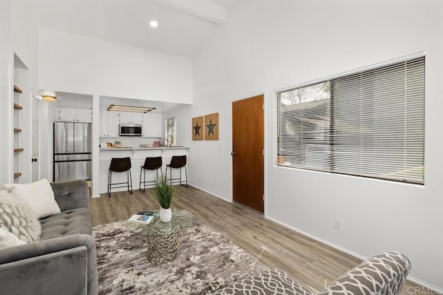 living room with high vaulted ceiling, beamed ceiling, light wood-type flooring, and baseboards