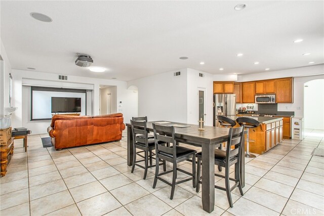 dining room featuring light tile patterned floors, visible vents, arched walkways, and recessed lighting