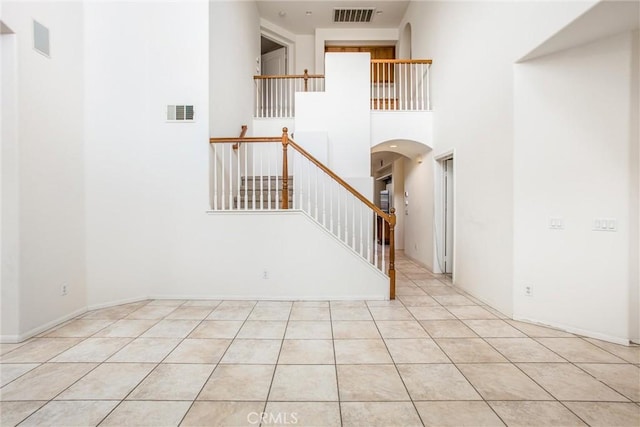 interior space featuring arched walkways, a high ceiling, visible vents, and tile patterned floors