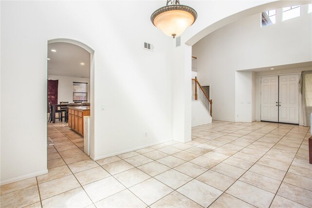 entrance foyer with arched walkways, light tile patterned flooring, recessed lighting, visible vents, and stairway