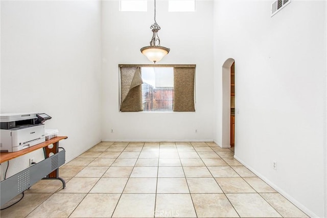 interior space featuring arched walkways, light tile patterned floors, and visible vents