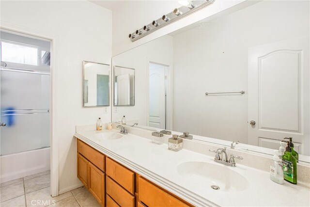 bathroom with double vanity, enclosed tub / shower combo, a sink, and tile patterned floors