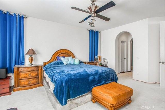 bedroom featuring a ceiling fan, arched walkways, and carpet flooring