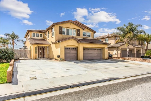 mediterranean / spanish home featuring driveway, an attached garage, fence, and stucco siding